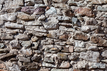 Obraz premium Close-up of a stone wall built with irregular rocks and mortar, suitable for architectural materials and natural textured backgrounds.