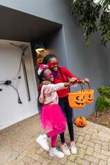 African American children standing on porch holding orange pumpkin buckets red blindfold pink tutu