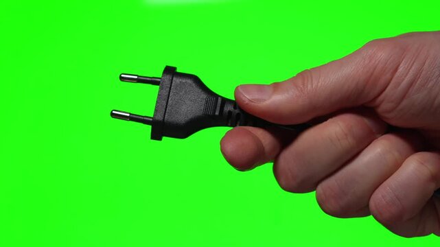 A close-up of a 220-volt high-voltage electrical plug.
A black electrical plug for an EA socket against a green background.