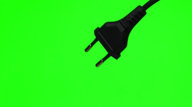 A close-up of a 220-volt high-voltage electrical plug.
A black electrical plug for an EA socket against a green background.