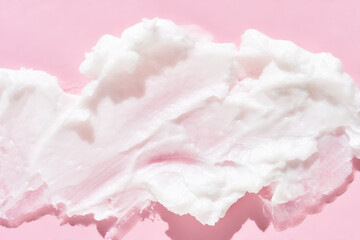 Smooth white cream texture on soft pink background for skincare and beauty concepts.