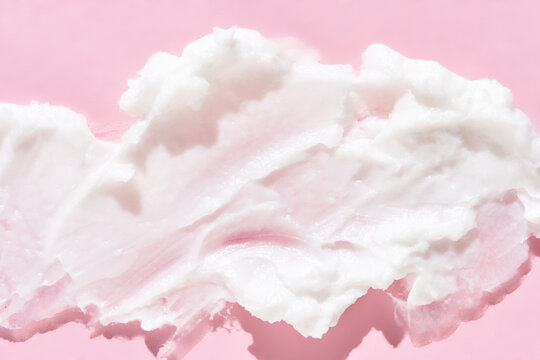 Smooth white cream texture on soft pink background for skincare and beauty concepts.