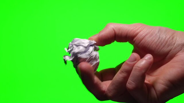 A close-up of a wrinkled paper ball on a green background.
Paper waste.
Used paper, crumpled by hand.
A damaged, wrinkled paper ball.