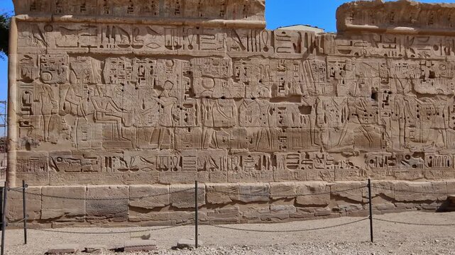 Closeup of ancient Egyptian hieroglyphic inscriptions with cartouches and bird symbols carved in sandstone wall at Medinet Habu temple in Luxor Egypt, detailed royal text.