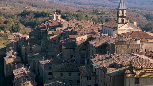 Aerial profile of Grotte di Castro hilltop town with churches and cascading houses. Drone view of authentic Italian village on tuff cliff, hidden gems of Italy Lazio. 4K 10-bit HDR cinematic footage.