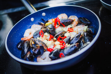 Apetyczne małże i krewetki smażone na patelni © Artur