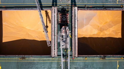 Bulk grain unloading into cargo ship hold at commercial port. © Emilio