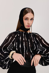 Naklejka premium Stylish young woman showcases elegant fashion in grey studio setting