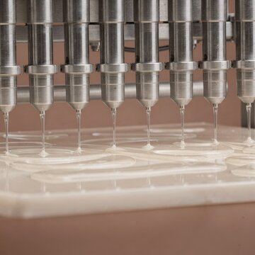 Precision engineered automated dispensing system releasing viscous material into custom shapes showcasing modern manufacturing technology and innovation in production processes