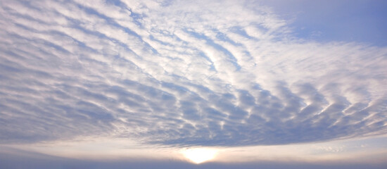 A serene sunset sky with layered clouds over a calm horizon