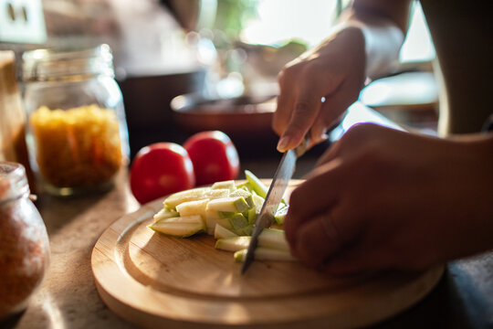 Person slicing pear on wooden cutting board in home kitchen