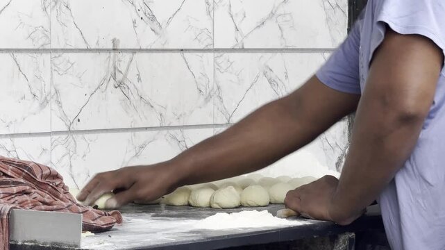 Editorial footage from Dharavi, Mumbai, India &mdash; January 28, 2026. Static ground-level close-up of a baker hand-rolling traditional flatbread dough in a local bakery.