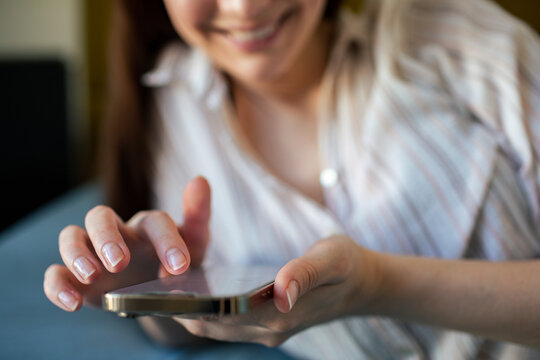 Smiling woman texting on smartphone at home