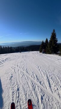 Beautiful POV ski landscape on the mountains. Skier skis down a snowy mountain trail in sunny weather.