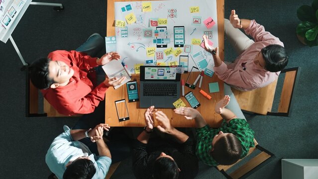 Top view of project manager using laptop working on Ux Ui design for mobile phone interface while marketing team designing software program by using brainstorming mind map. Time lapse. Convocation.