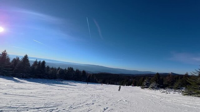 Beautiful POV ski landscape on the mountains. Skier skis down a snowy mountain trail in sunny weather.