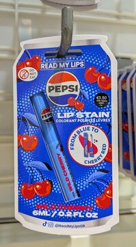 Lip stain con branding de Pepsi Wild Cherry, en envase con formato de lata de refresco. Expositor de tienda Primark en Madrid, Espa&ntilde;a