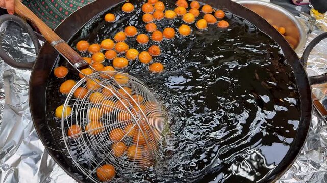 Ramadan dessert preparation at night market. Luqaimat frying in deep oil for iftar table, sweet Ramadan dessert served fresh. Traditional Ramadan dessert cooked live, Ramadan dessert street food style