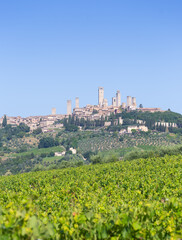 Obraz premium San Gimignano village, Italy: green countryside, blue sky, hill panorama with town and towers
