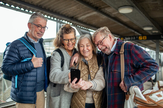 Senior friends taking a selfie at train station platform