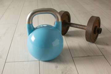 Blue Kettlebell and Rusty Dumbbell on Wooden Floor for Home Fitness