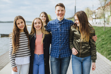 Group of diverse teenagers posing together, smiling and laughing outdoors, enjoying unity and...