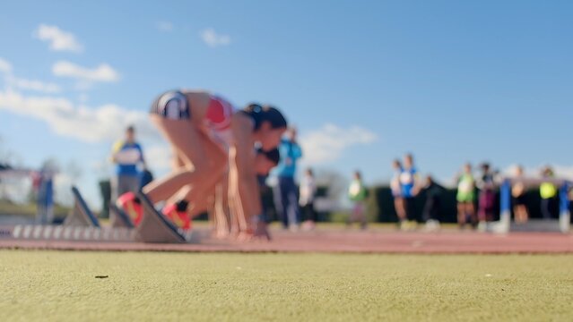 Sprinter in starting blocks on track and field, focused and ready for the race, representing determination, competition, and reaching goals at a sports event