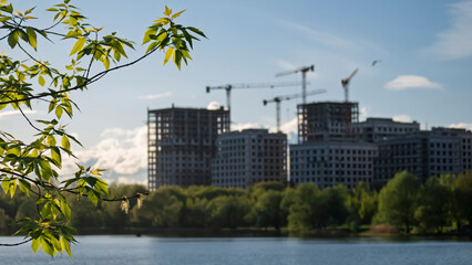 Bright Green Foliage Foreground with City Construction in Background over Water