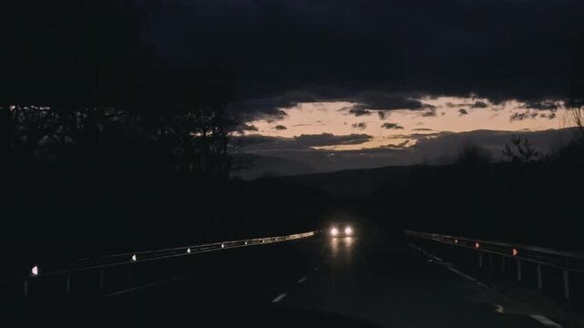 Melancholy trip on rainy pavement with flashing car beams
