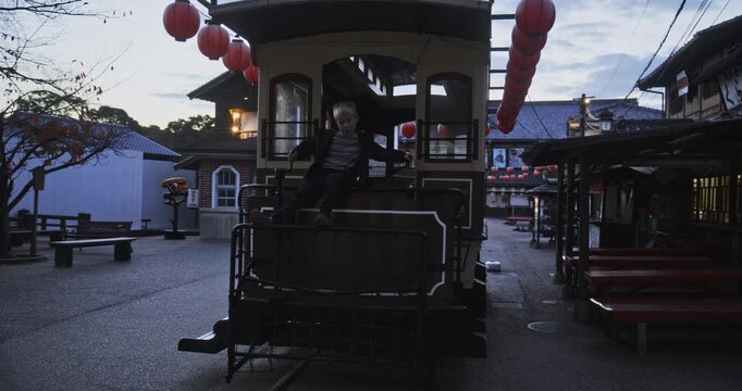 Silhouette of old Japanese tram as boy plays on it at dusk