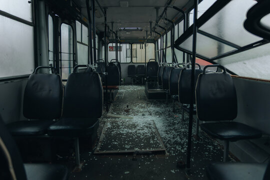 Interior of a public bus destroyed by an explosion with shattered glass covering the floor. Empty damaged passenger transport after a missile strike or terrorist attack. War in Ukraine, civilian infra