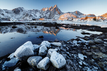 Snow covered rocks and mountain reflection in Arctic fjord at sunrise © radudumitrescu