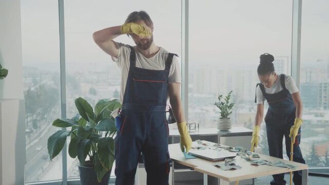 Worker rests quietly, Technician takes break after cleaning, Man pauses beside desk after thorough office cleaning