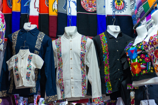 Collection of embroidered guayabera shirts in various colors.