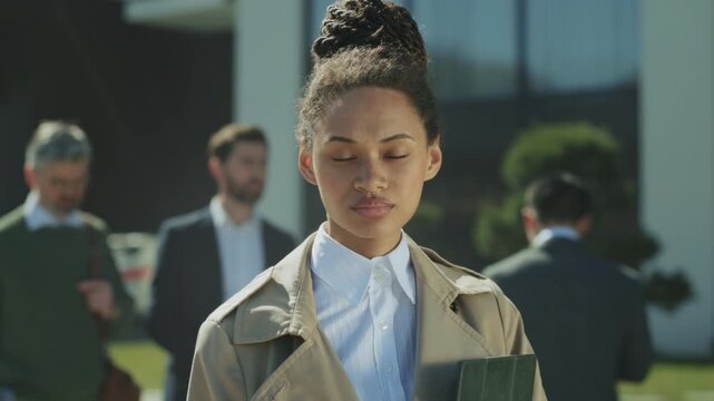 Young woman ready, Determined female professional in trench coat preparing for important meeting outdoors
