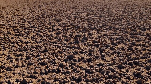 High resolution 4K aerial footage displaying freshly plowed farmland visible soil clumps deep furrows rich earthy texture highlighting agricultural preparation hardworking essence farming landscapes