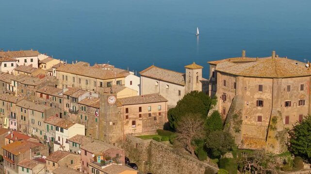 Capodimonte Farnese Castle and medieval village  70mm Close-up with Sailing Boat. Lake Bolsena Italy .Cinematic Drone Parallax Flight along Peninsula 4K