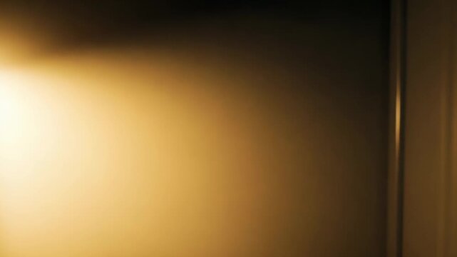 Golden light beam illuminating a hazy, ethereal atmosphere with subtle, glowing dust particles creating an abstract and warm background texture, perfect for overlays or design elements