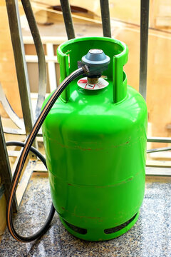 View of a green LPG cylinder with a pressure regulator and hose on a balcony used for cooking in apartments in Mediterranean countries.
