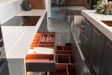 Open kitchen drawer with wooden organizer and lighting in luxury interior