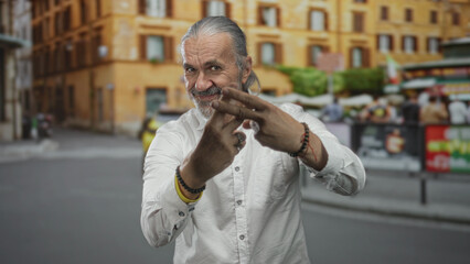 Man with long grey hair and beard making a hashtag gesture with fingers on a crowded city street in...