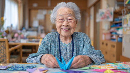 An elderly woman smiling while engaging in paper folding craft activity.