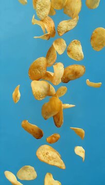 High speed 4K time lapse style shot of crispy golden potato chips dropping dynamically against blue background emphasizing crunch motion snack food 