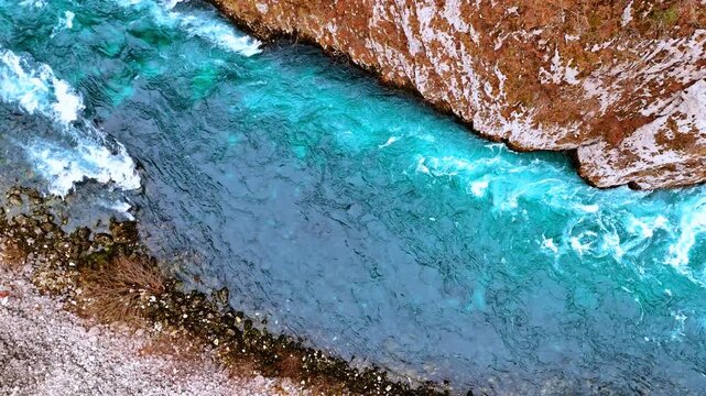 Turbulent narrow river with turquoise water flowing among the rocky banks. Drone footage over the stream in Montenegro.