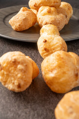 Fototapeta premium Cheese bread, a delicious Brazilian cheese bread, on a black plate on a dark surface, selective focus.