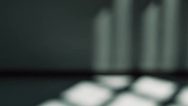 Sunlight coming through a window creating a rectangular grid shadow pattern on a dim floor in an abstract interior setting, highlighting light and darkness