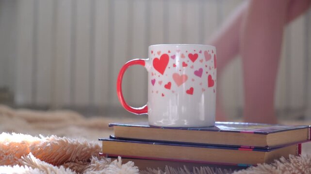 Sunlit living room, early morning, cup of tea with hearts pattern on foreground, books. Cozy authentic home, simple everyday life. Morning Routines