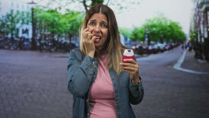 Fototapeta premium Woman holding toothpaste with hand on cheek on street, grimacing and touching teeth showing discomfort; toothache pain.