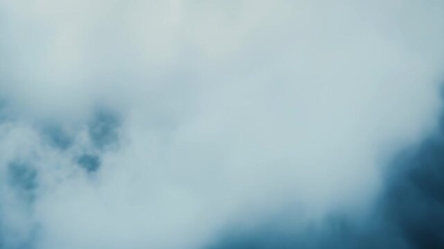 Dense swirling smoke and vapor fill the frame, forming an abstract, atmospheric backdrop of soft gray and blue gradients with mysterious, ethereal texture and motion