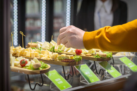 Cheese cubes served on wooden boards with toothpicks at food tasting counter in supermarket. Concept of food sampling, cheese tasting, retail promotion marketing
